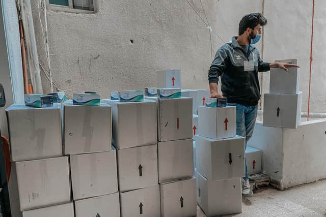 Basmeh & Zeitooneh volunteers helping beneficiaries carry the boxes containing food parcels and hygiene kits in a distribution centre in Karentina, Beirut.