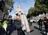 Police officers remove an oil-splattered statue of British Prime Minister Boris Johnson made by artist Hugo Farmer and installed by Greenpeace activists at Downing Street