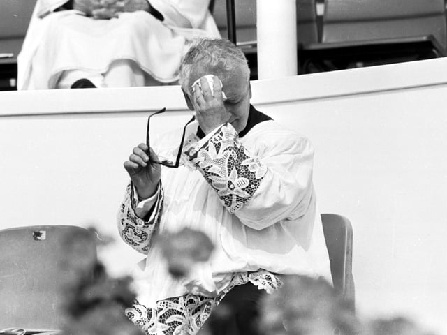 An unidentified priest feels the heat during Pope John Paul II's Mass at Bellahouston Park.