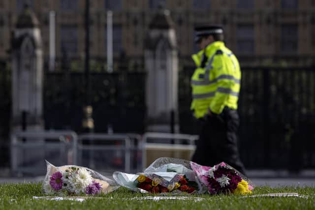 LONDON, ENGLAND - OCTOBER 16: A police officer walks past floral tributes left outside Parliament on October 16, 2021 in London, England. Counter-terrorism officers are investigating the murder of Sir David Amess, the Conservative MP for Southend West, who was stabbed to death during his constituency surgery yesterday around midday.  A man in his twenties was arrested at the scene. Home Secretary Priti Patel has ordered an immediate review of security measures for MPs. (Photo by Rob Pinney/Getty Images)