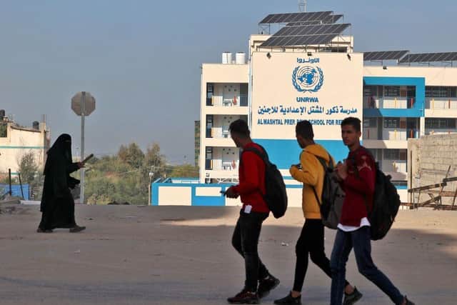 Palestinians walk past the headquarters of the United Nations Relief and Works Agency for Refugees (UNRWA) in Gaza City.