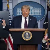 President Donald Trump holds a mask as he speaks during a news conference at the White House, Tuesday, July 21, 2020, in Washington. (AP Photo/Evan Vucci).