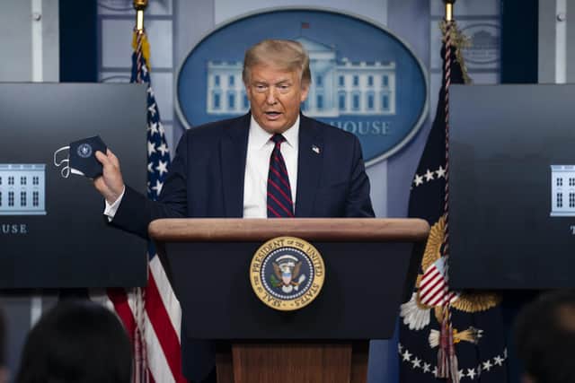 President Donald Trump holds a mask as he speaks during a news conference at the White House, Tuesday, July 21, 2020, in Washington. (AP Photo/Evan Vucci).