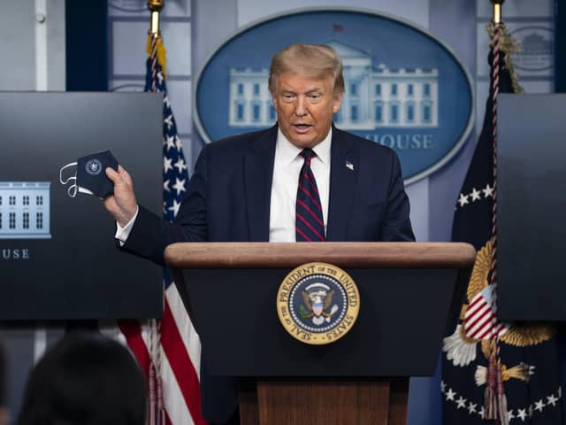 President Donald Trump holds a mask as he speaks during a news conference at the White House, Tuesday, July 21, 2020, in Washington. (AP Photo/Evan Vucci).