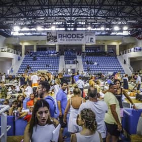 Evacuees sit inside a stadium following their evacuation during a forest fire on the island of Rhodes