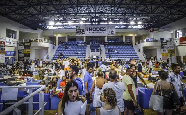 Evacuees sit inside a stadium following their evacuation during a forest fire on the island of Rhodes