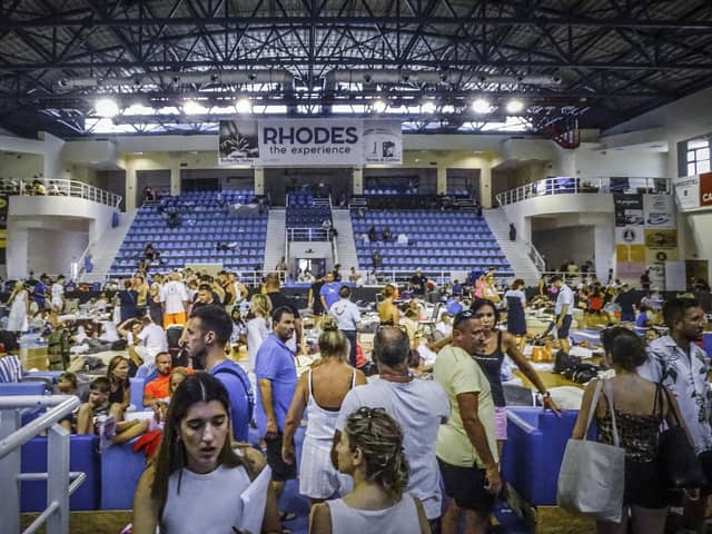 Evacuees sit inside a stadium following their evacuation during a forest fire on the island of Rhodes