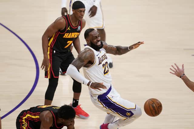 LeBron James grimaces as he trips and injures himself against Atlanta Hawks forward Tony Snell. Picture: Marcio Jose Sanchez/AP