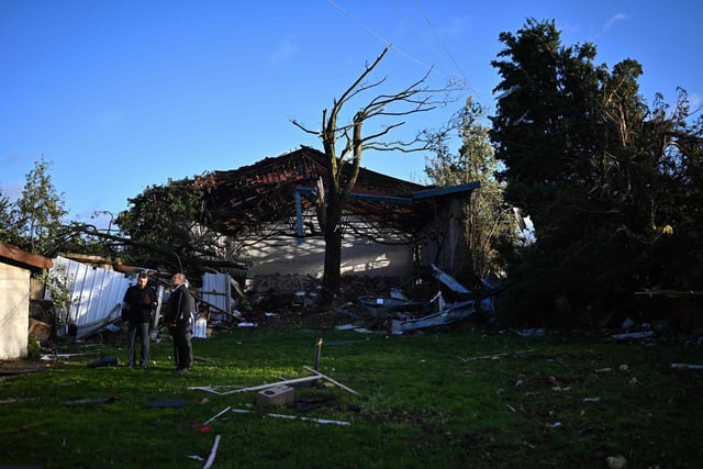 Local residents stand next to a damaged building in Bihucourt, northern France, on October 24, 2022 after a tornado hit the region. (Photo by Sameer Al-Doumy)