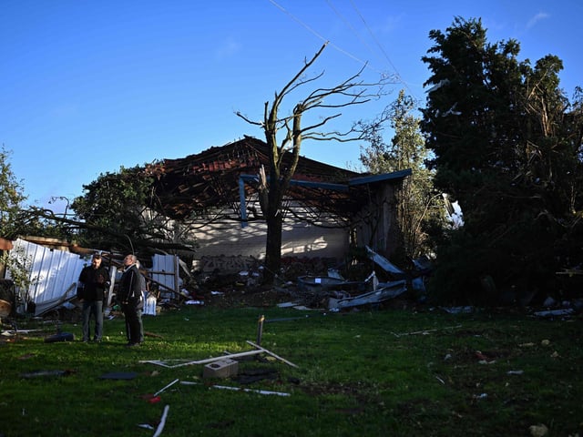 Local residents stand next to a damaged building in Bihucourt, northern France, on October 24, 2022 after a tornado hit the region. (Photo by Sameer Al-Doumy)