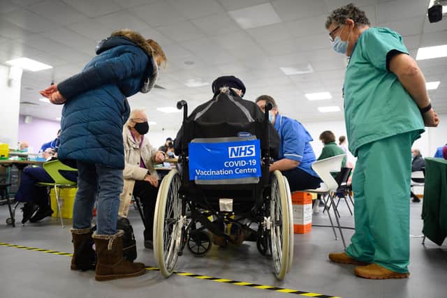 A man waits in a wheelchair for his coronavirus vaccination. Photo by Leon Neal / POOL / AFP
