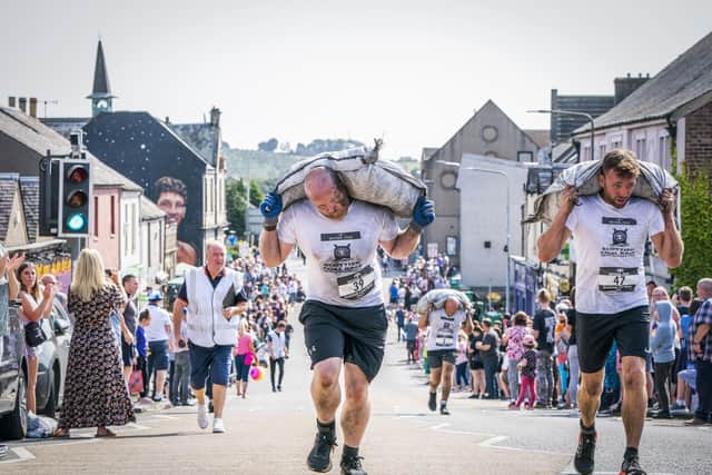Competitors take part in the Scottish Coal Carrying Championships through the streets of Kelty in Fife.  Picture date: Saturday August 28, 2021. PA Photo. The annual event is one of only two Coal Races in the world and the men's race requires participants to carry a 50-kilo bag of coal and the women's race requires a 25-kilo bag of coal to be carried over 1000 metres through the village. Photo credit should read: Jane Barlow/PA Wire 