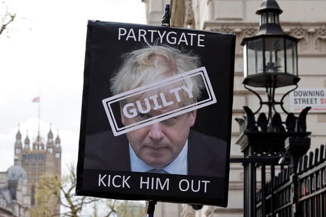 A demonstrator poses for a photograph holding a placard calling for the resignation of Boris Johnson