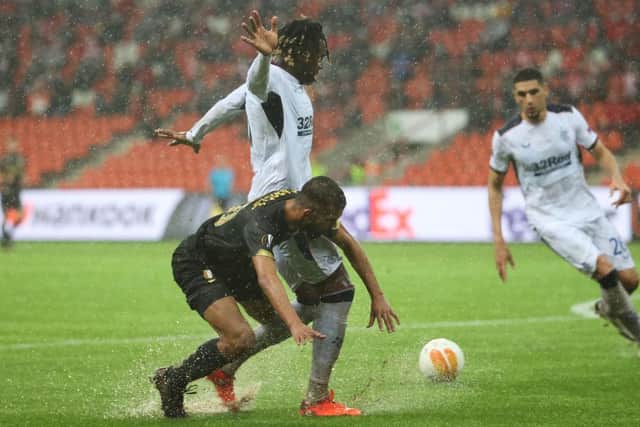 Standard's Mehdi Carcela and Rangers' Calvin Bassey fight for the ball on the waterlogged pitch (Photo by VIRGINIE LEFOUR/BELGA MAG/AFP via Getty Images)