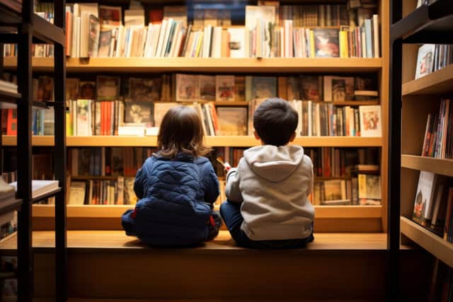 two children sitting in a bookstore, looking at shelves filled with books, and talking about the books