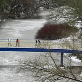 Walkers crossing Ha'penny Bridge over a frozen River Kelvin in Glasgow on Friday. Picture: John Devlin