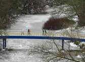 Walkers crossing Ha'penny Bridge over a frozen River Kelvin in Glasgow on Friday. Picture: John Devlin