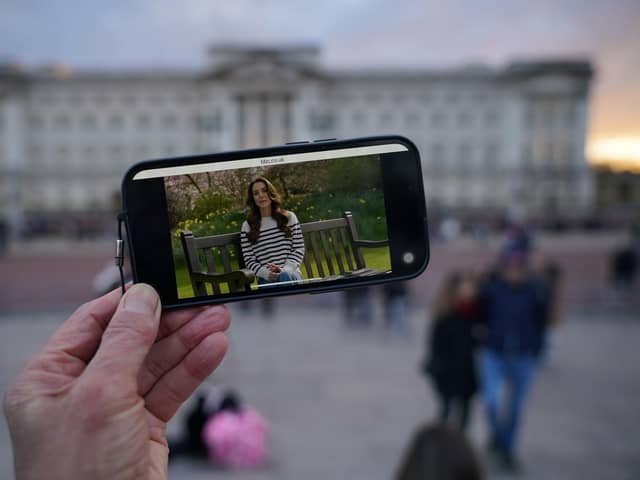 A person watches an announcement on a smart phone outside Buckingham Palace by the Princess of Wales, who has revealed she is undergoing chemotherapy treatment for cancer.. Photo: Yui Mok/PA Wire