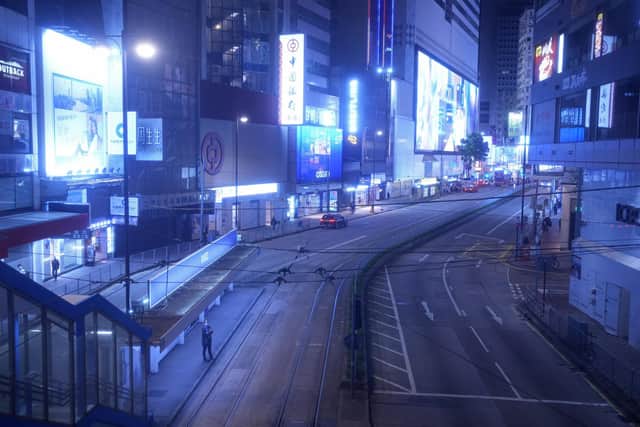 A woman stands on an empty street usually packed with shoppers in Causeway Bay, a famous shopping district in Hong Kong
