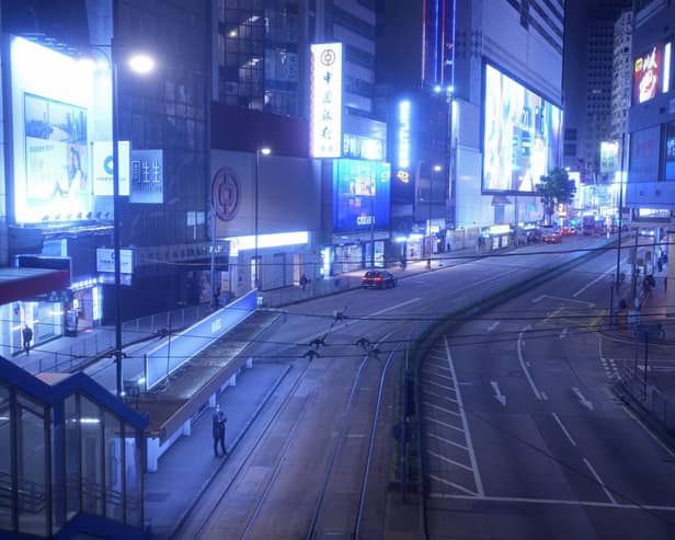 A woman stands on an empty street usually packed with shoppers in Causeway Bay, a famous shopping district in Hong Kong