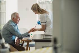 A man receives a blood test at home from a nurse