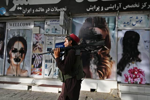 A Taliban fighter walks past a beauty salon with images of women defaced using spray paint in Kabul on Wednesday (Picture: Wakil Kohsar/AFP via Getty Images)