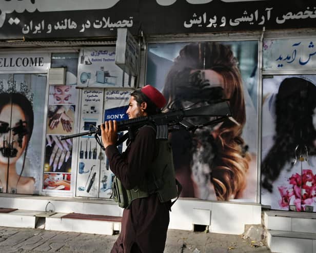 A Taliban fighter walks past a beauty salon with images of women defaced using spray paint in Kabul on Wednesday (Picture: Wakil Kohsar/AFP via Getty Images)