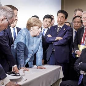 In one of the least diplomatic photos ever,  German Chancellor Angela Merkel speaks with U.S. President Donald Trump, seated at right, during the G7 Leaders Summit in La Malbaie, Quebec, Canada, on Saturday, June 9, 2018.  Trump left the summit early and refused to endorse the official statement - calling Canadian Prime Minister Justin Trudeau "very dishonest and weak"