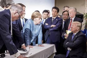 In one of the least diplomatic photos ever,  German Chancellor Angela Merkel speaks with U.S. President Donald Trump, seated at right, during the G7 Leaders Summit in La Malbaie, Quebec, Canada, on Saturday, June 9, 2018.  Trump left the summit early and refused to endorse the official statement - calling Canadian Prime Minister Justin Trudeau "very dishonest and weak"