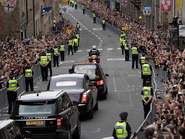 Police stand guard as the Queen's coffin travels down the Royal Mile in Edinburgh