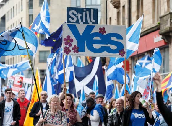 People taking part in the March for Independence wave Saltires as they process through Glasgow city centre.