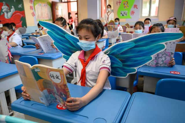 Primary school pupils wear wings to help maintain social distancing in a classroom in Taiyuan in China's northern Shanxi province. (Picture: AFP via Getty Images)