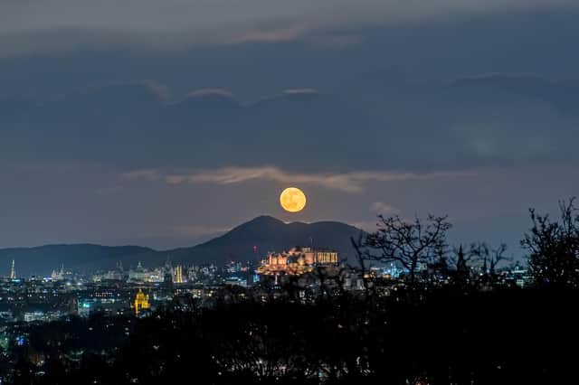 This spectacular image shows a ghostly, spectre-like moon hanging above Edinburgh Castle