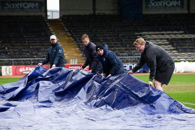 Dundee groundsmen relay the pitch covers earlier in the day.