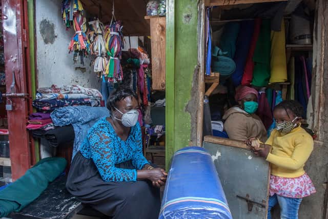 A woman who trades in fabrics and her child wear face masks as preventive measure against Covid-19 in a shop in Lilongwe City market (Picture: Amos Gumulira/AFP via Getty Images)
