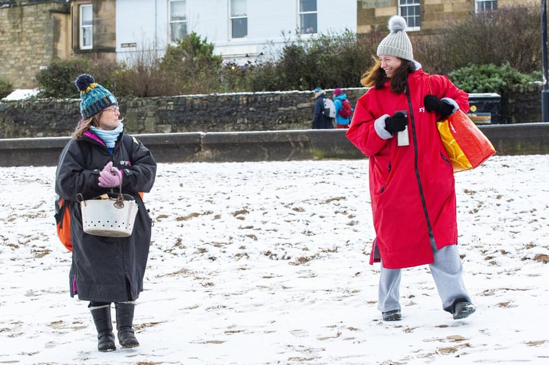 Maree Rudd (black robe) and Isabella McNamara (red robe) head to the snowy beach for a dip