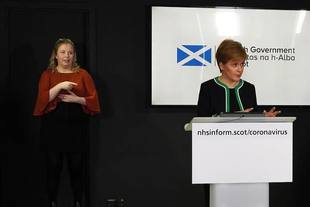 A sign language interpreter (L) working as Scotland's First Minister, Nicola Sturgeon speaks during the Scottish government's daily briefing on coronavirus (Photo by -/Scottish Government/AFP via Getty Images)
