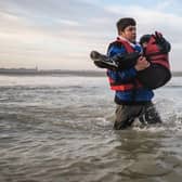 A man carries a child as he runs to board a smuggler's boat in northern France last month, in an attempt to cross the English Channel.