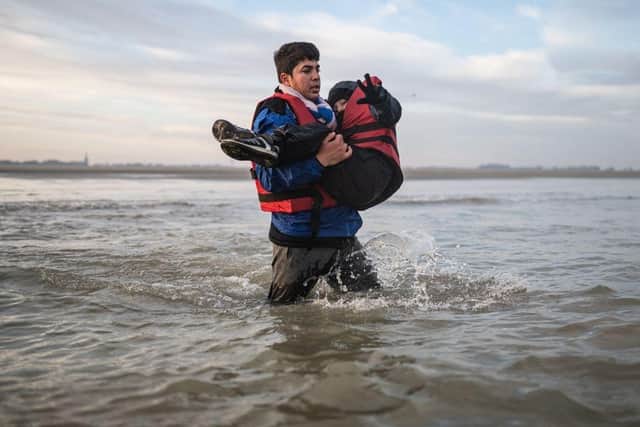 A man carries a child as he runs to board a smuggler's boat in northern France last month, in an attempt to cross the English Channel.