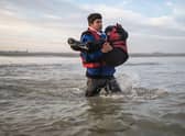 A man carries a child as he runs to board a smuggler's boat in northern France last month, in an attempt to cross the English Channel.