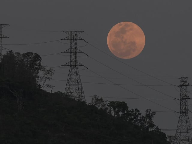 A full moon rises behind the high voltage towers of the El Avila in Caracas, Venezuela, Sunday, May 15, 2022 (AP Photo/Matias Delacroix)