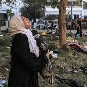 A woman reacts while holding a pillow as she stands amid debris outside the site of the Ahli Arab hospital in central Gaza in the aftermath of an overnight strike there. Photo: AFP via Getty Images