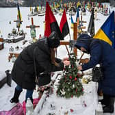 The wife and the mother of Oleg Skybyk, a Ukrainian soldier killed resisting the Russian invasion, decorate a Christmas tree on his grave (Picture: Yuriy Dyachyshyn/AFP via Getty Images)