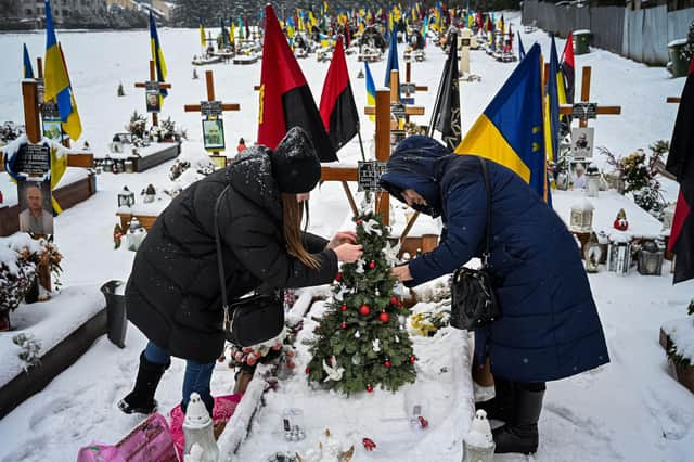 The wife and the mother of Oleg Skybyk, a Ukrainian soldier killed resisting the Russian invasion, decorate a Christmas tree on his grave (Picture: Yuriy Dyachyshyn/AFP via Getty Images)