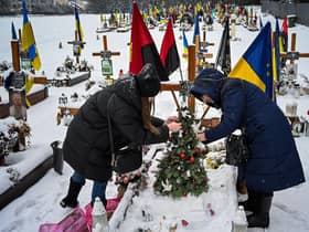 The wife and the mother of Oleg Skybyk, a Ukrainian soldier killed resisting the Russian invasion, decorate a Christmas tree on his grave (Picture: Yuriy Dyachyshyn/AFP via Getty Images)