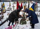 The wife and the mother of Oleg Skybyk, a Ukrainian soldier killed resisting the Russian invasion, decorate a Christmas tree on his grave (Picture: Yuriy Dyachyshyn/AFP via Getty Images)