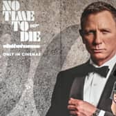 A woman walks past a poster for the new James Bond movie No Time to Die in Bangkok (Picture: Mladen Antonov/AFP via Getty Images)