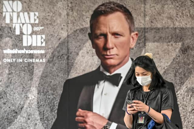 A woman walks past a poster for the new James Bond movie No Time to Die in Bangkok (Picture: Mladen Antonov/AFP via Getty Images)