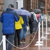 People queue to vote in the rain outside the polling station at Notre Dame Primary School in Glasgow.