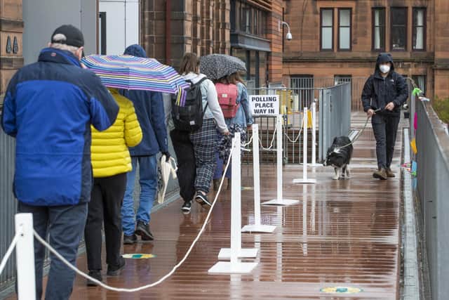 People queue to vote in the rain outside the polling station at Notre Dame Primary School in Glasgow.